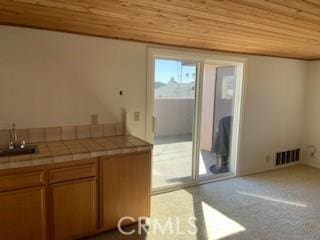 kitchen with visible vents, tile countertops, brown cabinets, wooden ceiling, and a sink