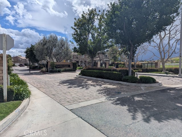 view of street featuring a gate, curbs, and a gated entry