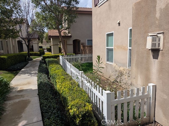 view of property exterior with stucco siding, a tiled roof, and fence