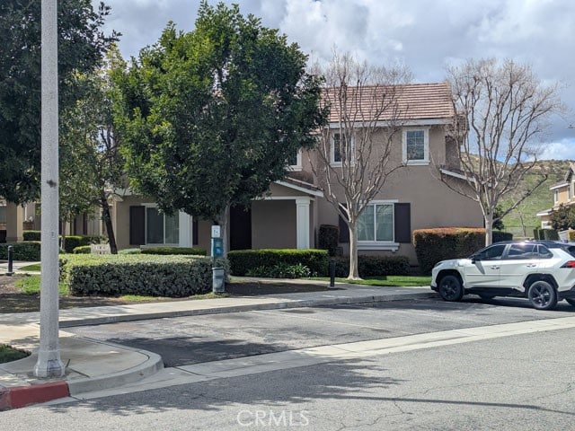 view of front of property with a tile roof, uncovered parking, and stucco siding