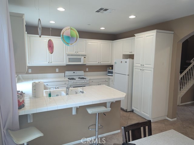 9770 Winterberry Dr, Riverside, CA 92803 - kitchen with visible vents, a sink, light tile patterned floors, a peninsula, and white appliances