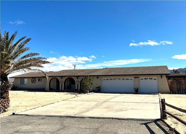 ranch-style home featuring stucco siding, driveway, a garage, and fence