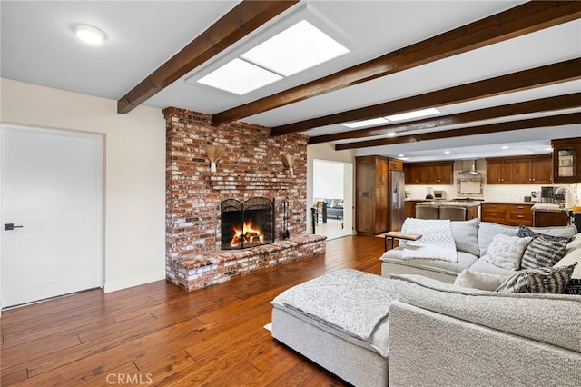 living room featuring dark wood finished floors, a brick fireplace, baseboards, and beamed ceiling