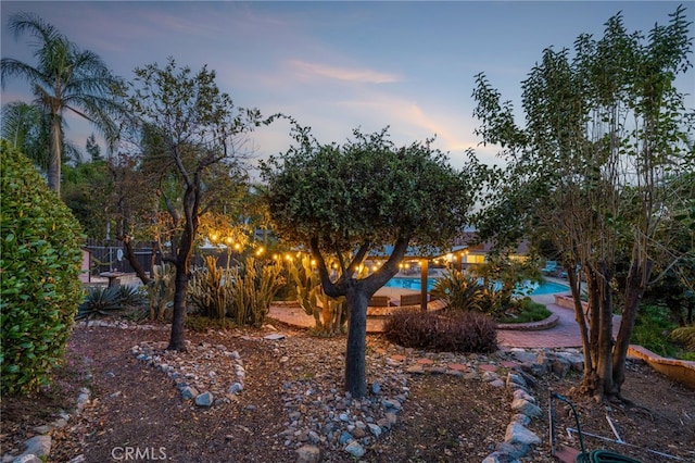 yard at dusk with an outdoor pool and fence