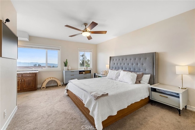 bedroom featuring baseboards, light colored carpet, and ceiling fan