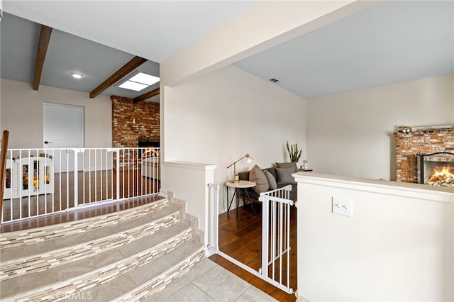 hall featuring an upstairs landing, beamed ceiling, and wood finished floors