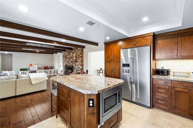 kitchen with visible vents, stainless steel appliances, decorative backsplash, open floor plan, and a center island