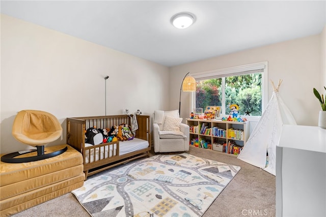 bedroom featuring a nursery area and carpet