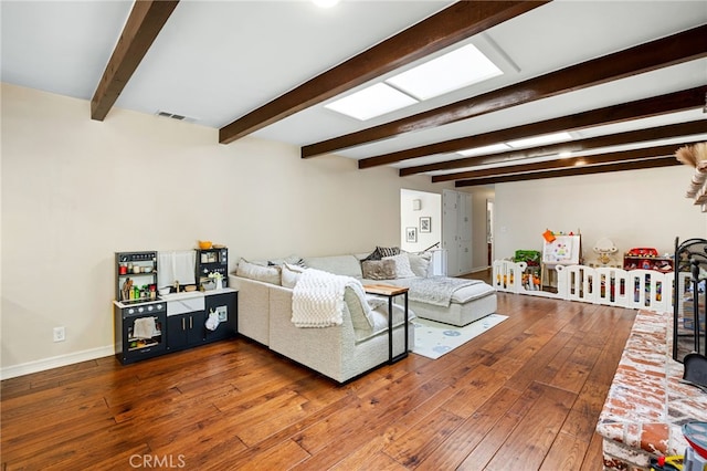 living area featuring visible vents, baseboards, beamed ceiling, and hardwood / wood-style floors