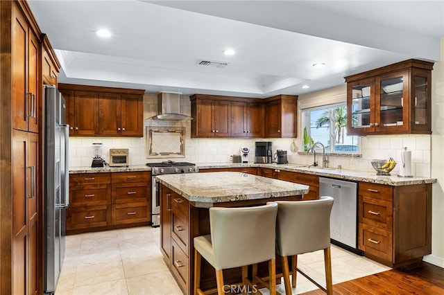 kitchen with visible vents, decorative backsplash, appliances with stainless steel finishes, wall chimney exhaust hood, and a raised ceiling