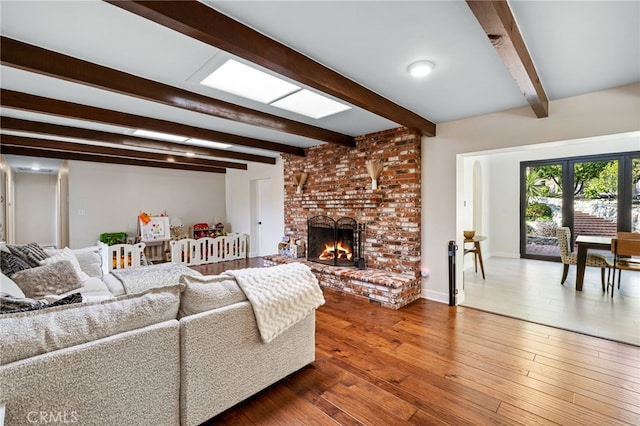 living area featuring dark wood finished floors, beam ceiling, a fireplace, and baseboards