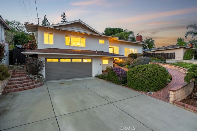 traditional home with stucco siding, an attached garage, a chimney, and driveway