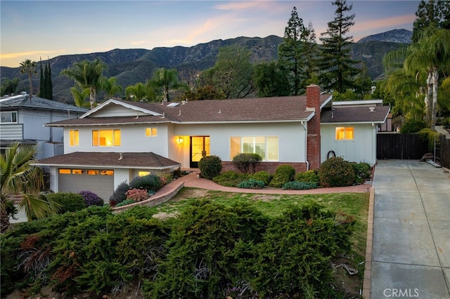 view of front of home featuring a mountain view, a chimney, an attached garage, and fence