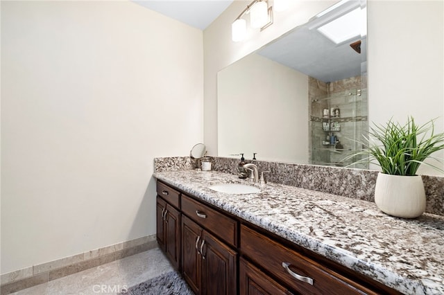 bathroom with baseboards, a shower stall, and vanity