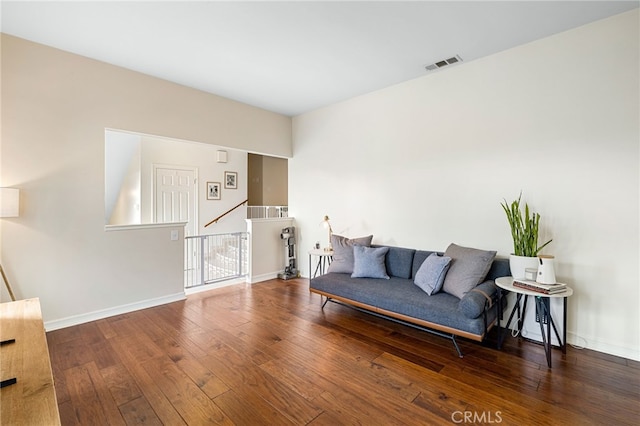 living area featuring an upstairs landing, visible vents, baseboards, and hardwood / wood-style floors