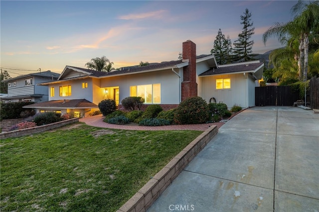 view of front of home featuring a front lawn, a chimney, driveway, and fence