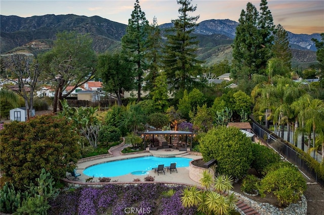 outdoor pool with a mountain view, a patio, and fence