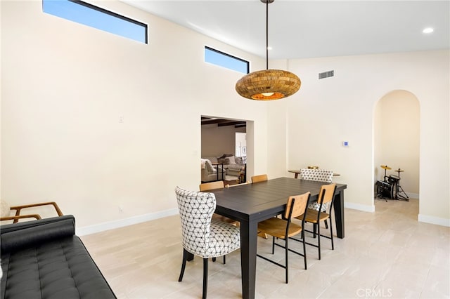 dining area with visible vents, baseboards, recessed lighting, a towering ceiling, and arched walkways