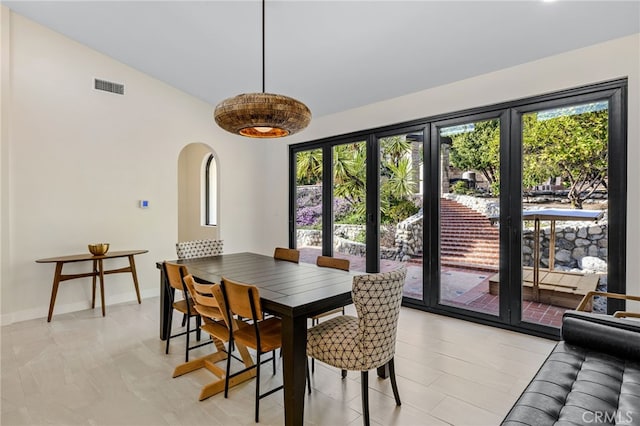 dining space featuring visible vents, arched walkways, and baseboards