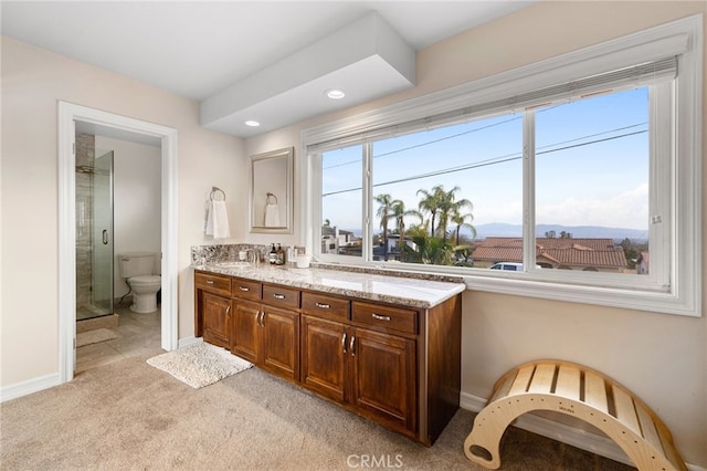 bathroom with toilet, a stall shower, a sink, double vanity, and baseboards