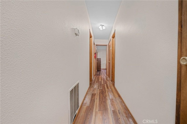 hallway featuring visible vents and light wood-type flooring