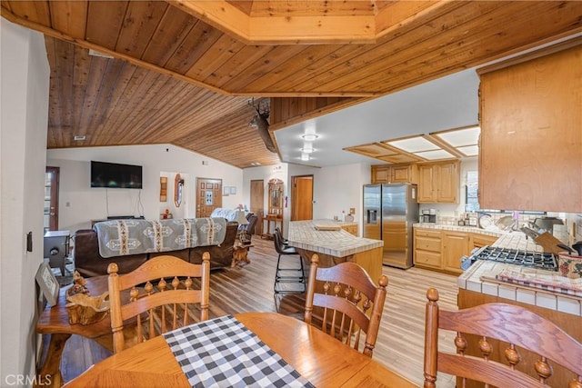 dining room featuring vaulted ceiling, light wood-style flooring, and wooden ceiling