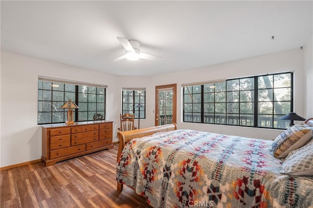 bedroom with multiple windows, baseboards, and wood finished floors