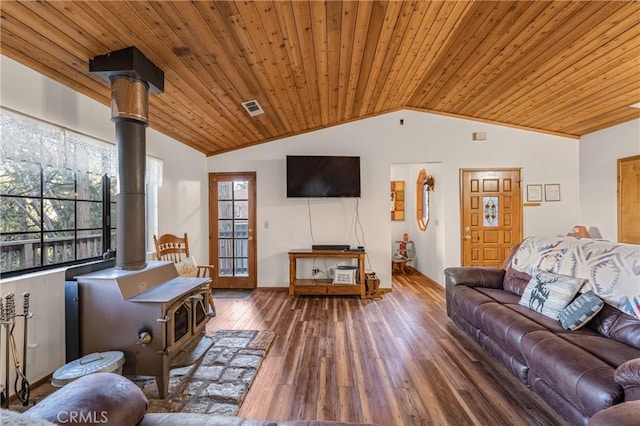 living area featuring lofted ceiling, a wealth of natural light, wooden ceiling, a wood stove, and wood finished floors