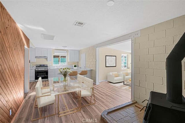 living area featuring light wood-style flooring, wooden walls, and visible vents