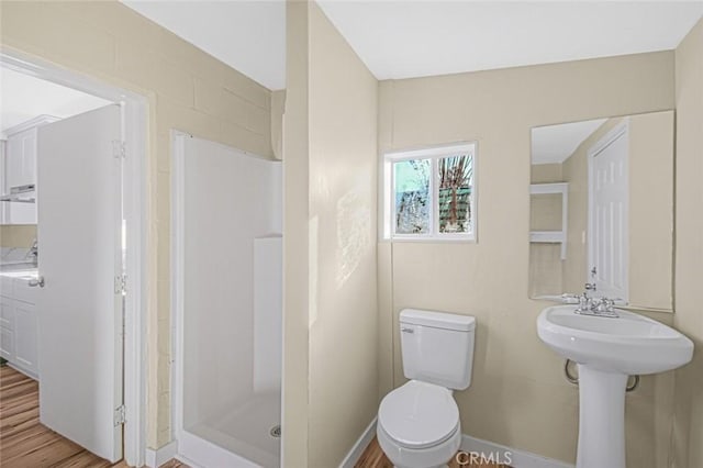 full bath with baseboards, wood finished floors, toilet, and a stall shower