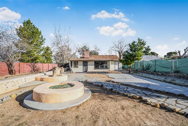 back of house featuring stucco siding, fence, and a chimney