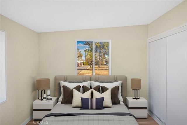 bedroom with wood finished floors, a closet, and baseboards