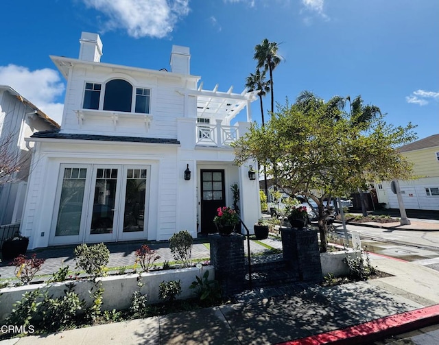 view of front facade featuring a chimney and a balcony