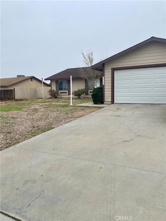 view of front of home featuring concrete driveway, an attached garage, and fence