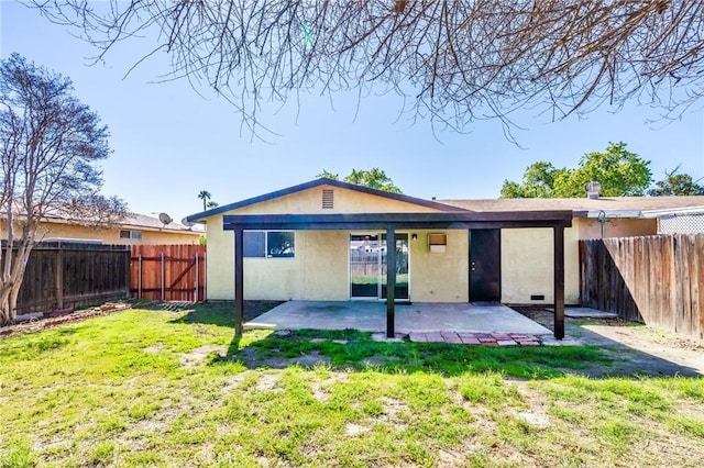 rear view of property with a fenced backyard, stucco siding, a patio, and a yard