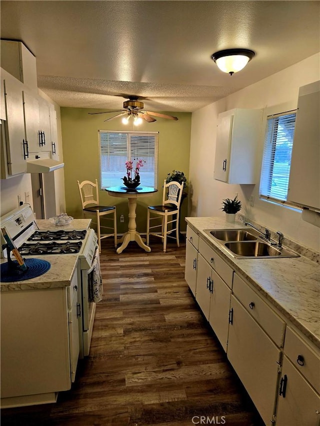 kitchen featuring a sink, dark wood-style floors, white cabinetry, white range with gas stovetop, and ceiling fan