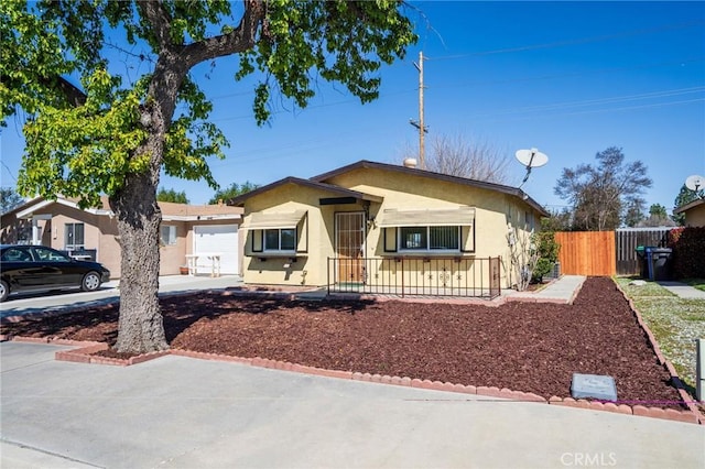 view of front facade featuring stucco siding, driveway, a garage, and fence