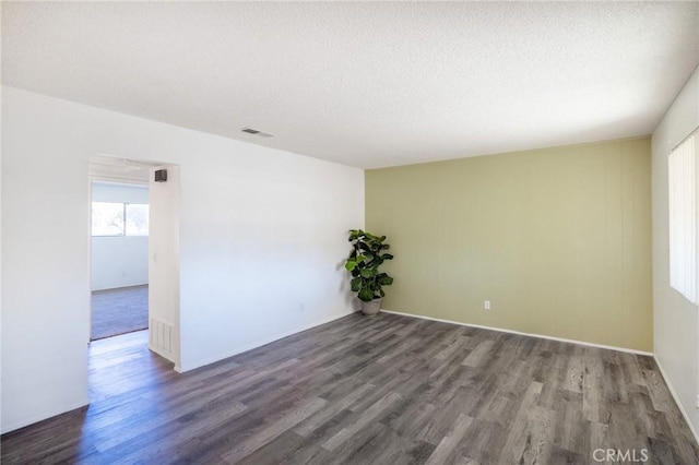 empty room featuring wood finished floors, visible vents, and a textured ceiling