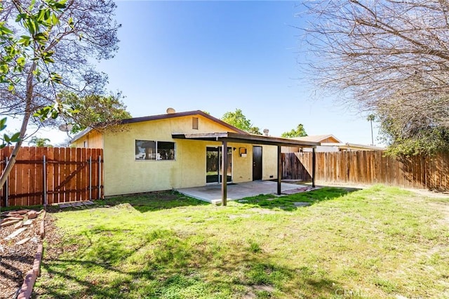 rear view of property with a patio area, a lawn, a fenced backyard, and stucco siding