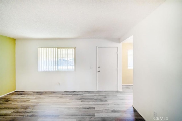 empty room featuring baseboards, a textured ceiling, and wood finished floors