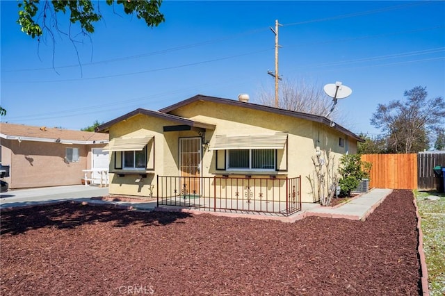 view of front of home with stucco siding, a patio, and fence