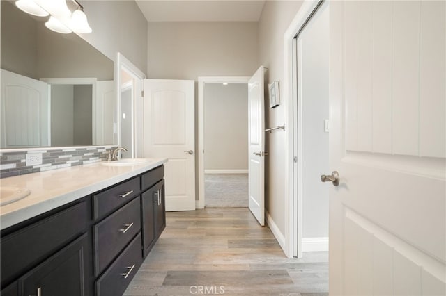 bathroom featuring tasteful backsplash, a sink, double vanity, and wood finished floors