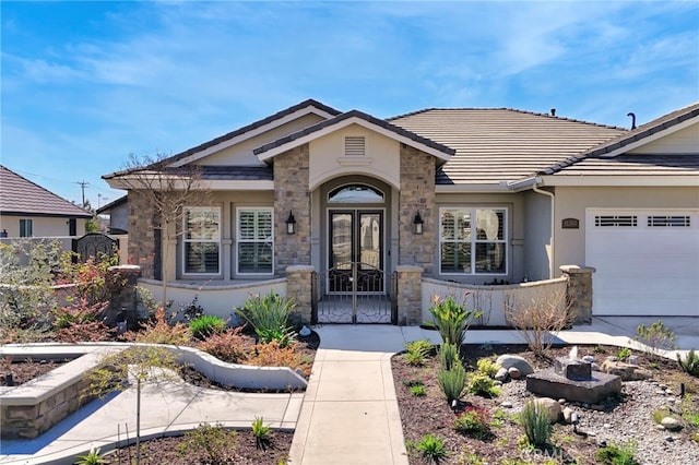 property entrance with a tiled roof, stone siding, french doors, and an attached garage