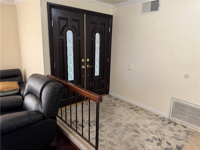 carpeted foyer with visible vents, baseboards, and ornamental molding