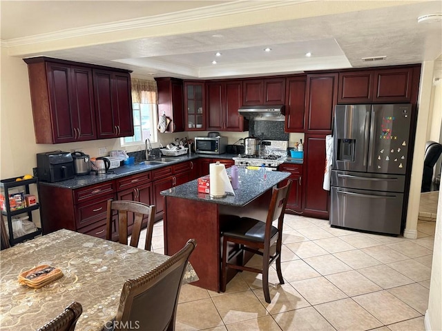 kitchen with a tray ceiling, reddish brown cabinets, and stainless steel appliances