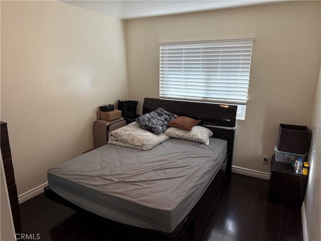 bedroom featuring multiple windows, wood finished floors, and baseboards