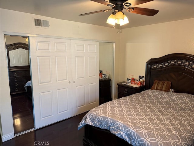 bedroom with a closet, visible vents, dark wood finished floors, and a ceiling fan