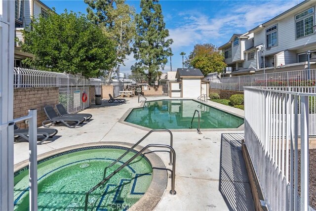 11150 Glenoaks Blvd Unit 266, Pacoima, CA 91331 - community pool featuring fence, a community hot tub, an outdoor structure, a storage unit, and a patio area