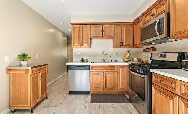 kitchen with a sink, stainless steel appliances, brown cabinets, and light countertops