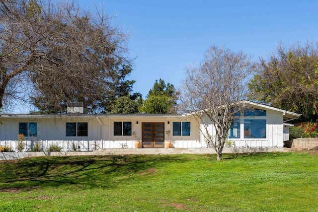 view of front facade featuring a front lawn, french doors, and board and batten siding